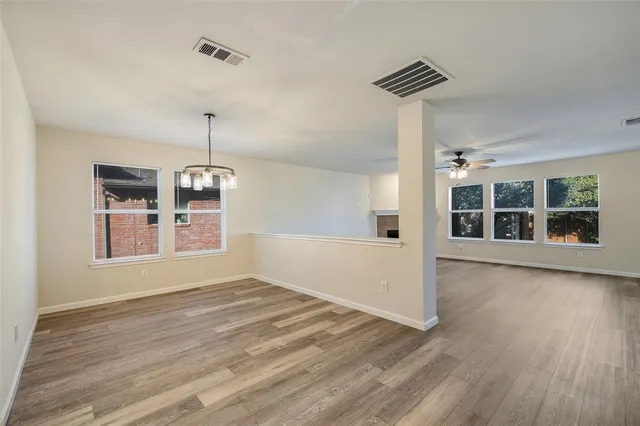 a view of an empty room with a window and wooden floor