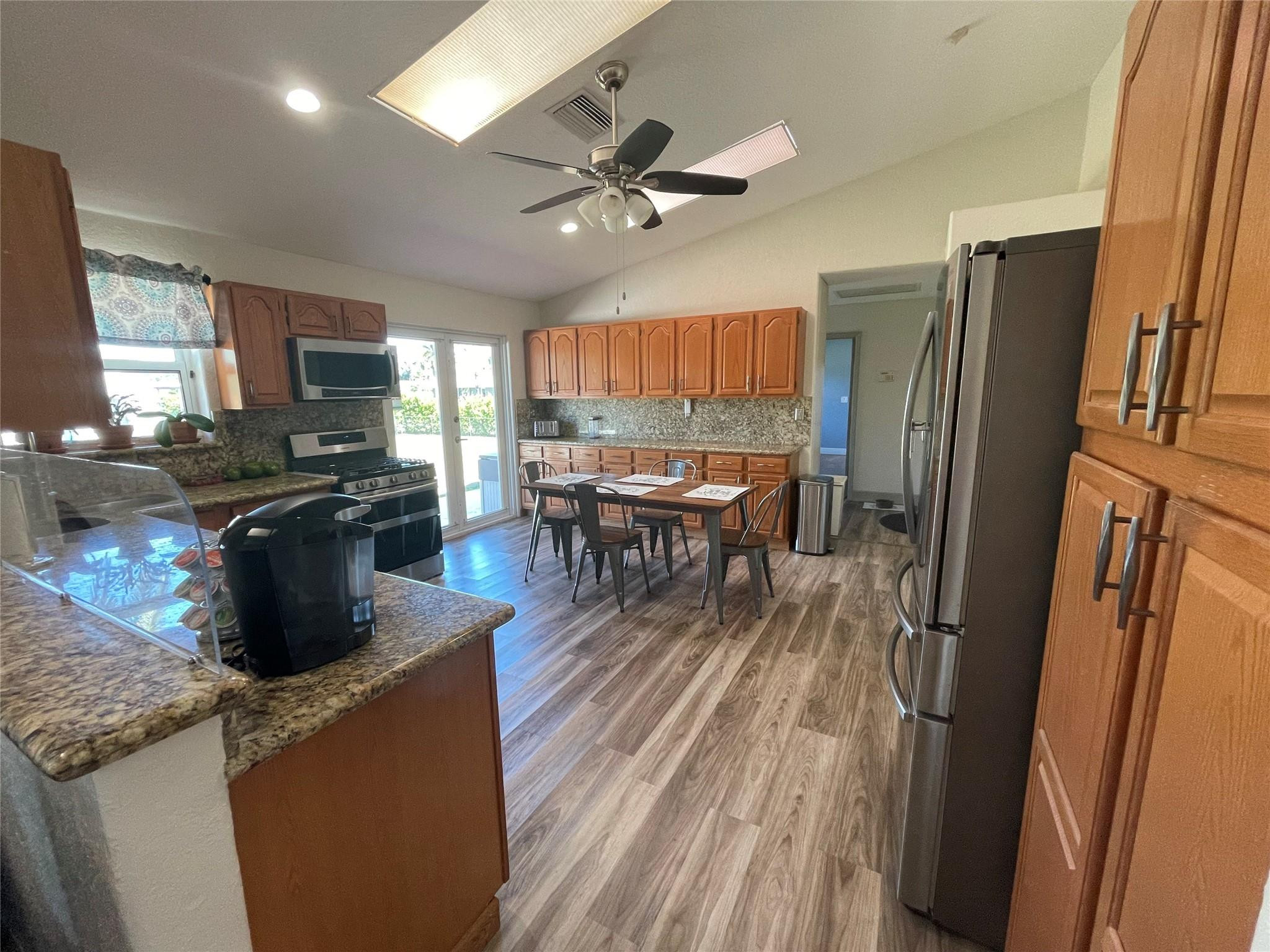 17001 Southwest 48th Street Southwest Ranches, FL 33331 - Photo 18 of 35 a kitchen with stainless steel appliances granite countertop a refrigerator a stove a sink a dining table and chairs with wooden floor