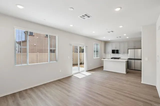 a view of kitchen with granite countertop refrigerator oven sink and white cabinets with wooden floor