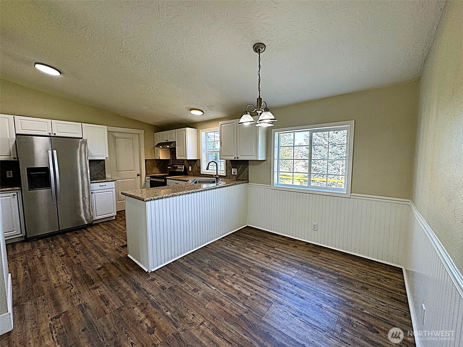 6883 Ferguson Road Northeast Moses Lake, WA 98837 - Photo 8 of 39 a kitchen with stainless steel appliances kitchen island granite countertop a refrigerator a stove a microwave oven a sink with wooden floor and cabinets