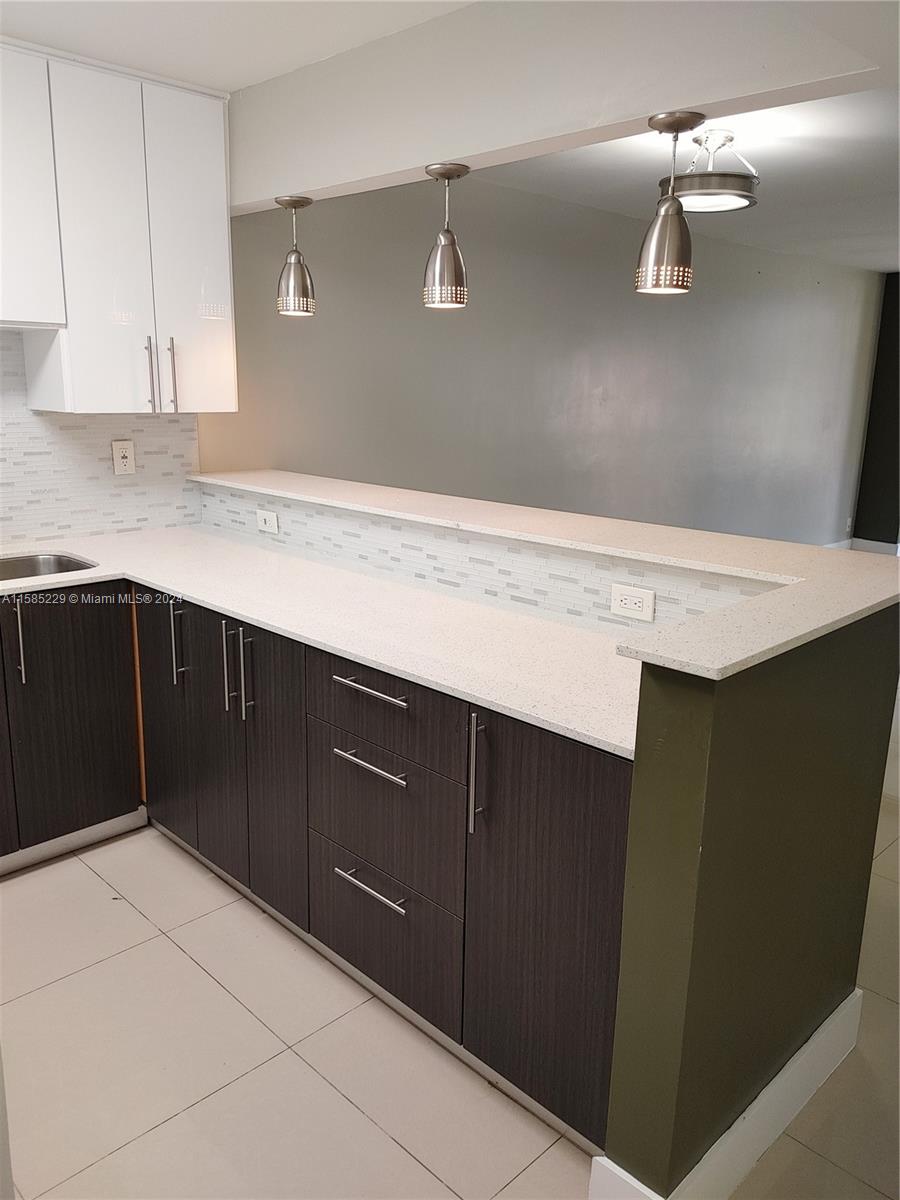 8330 Sands Point Boulevard, Unit N107 Tamarac, FL 33321 - Photo 4 of 13 a kitchen with a sink and cabinets