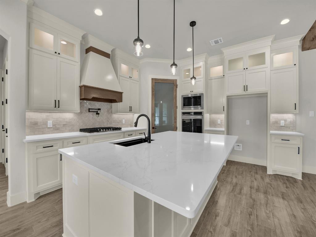 313 Wrangler Court Weatherford, TX 76088 - Photo 17 of 40 a large kitchen with kitchen island a stove a sink a center island a refrigerator and a wooden floor