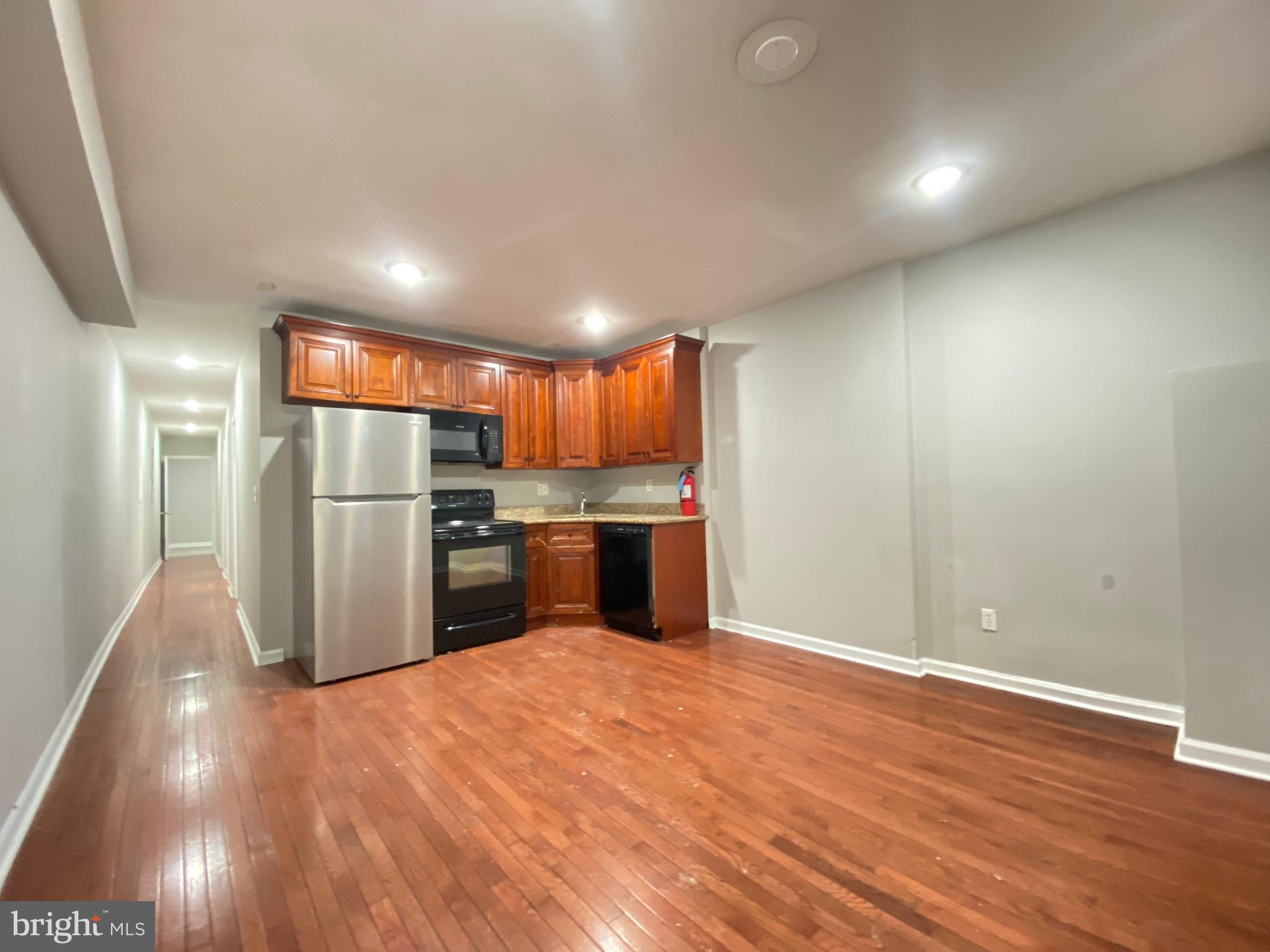 a kitchen with stainless steel appliances a refrigerator and a wooden floor