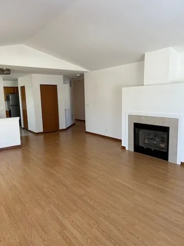 a view of an empty room with wooden floor and a fireplace