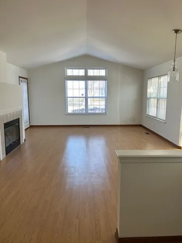 an empty room with wooden floor fireplace and windows