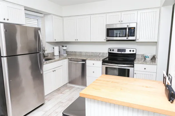 a kitchen with stainless steel appliances a refrigerator a stove a sink and a dining table