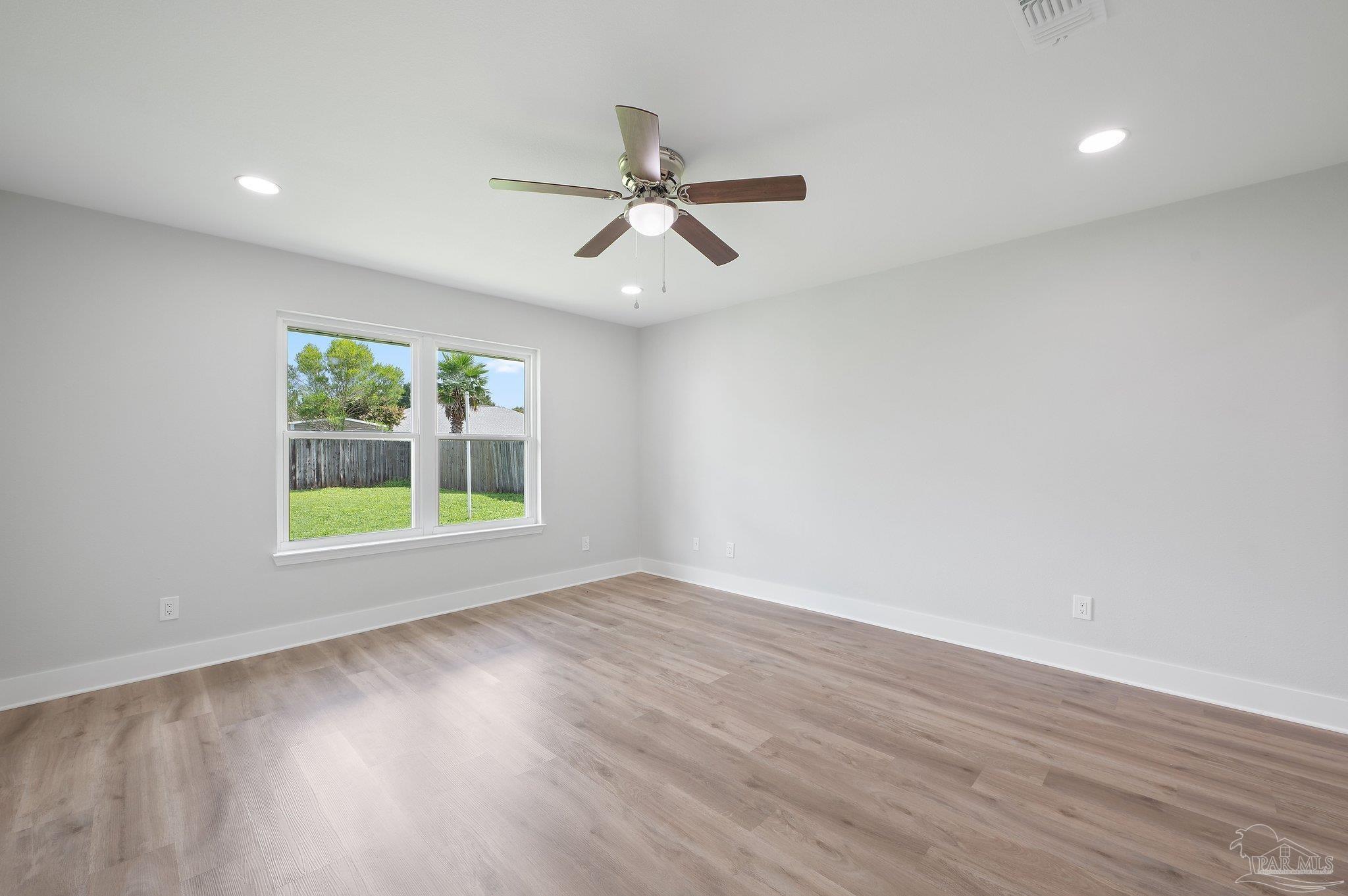 4290 Idell Lane Pace, FL 32571 - Photo 21 of 45 an empty room with wooden floor fan and windows