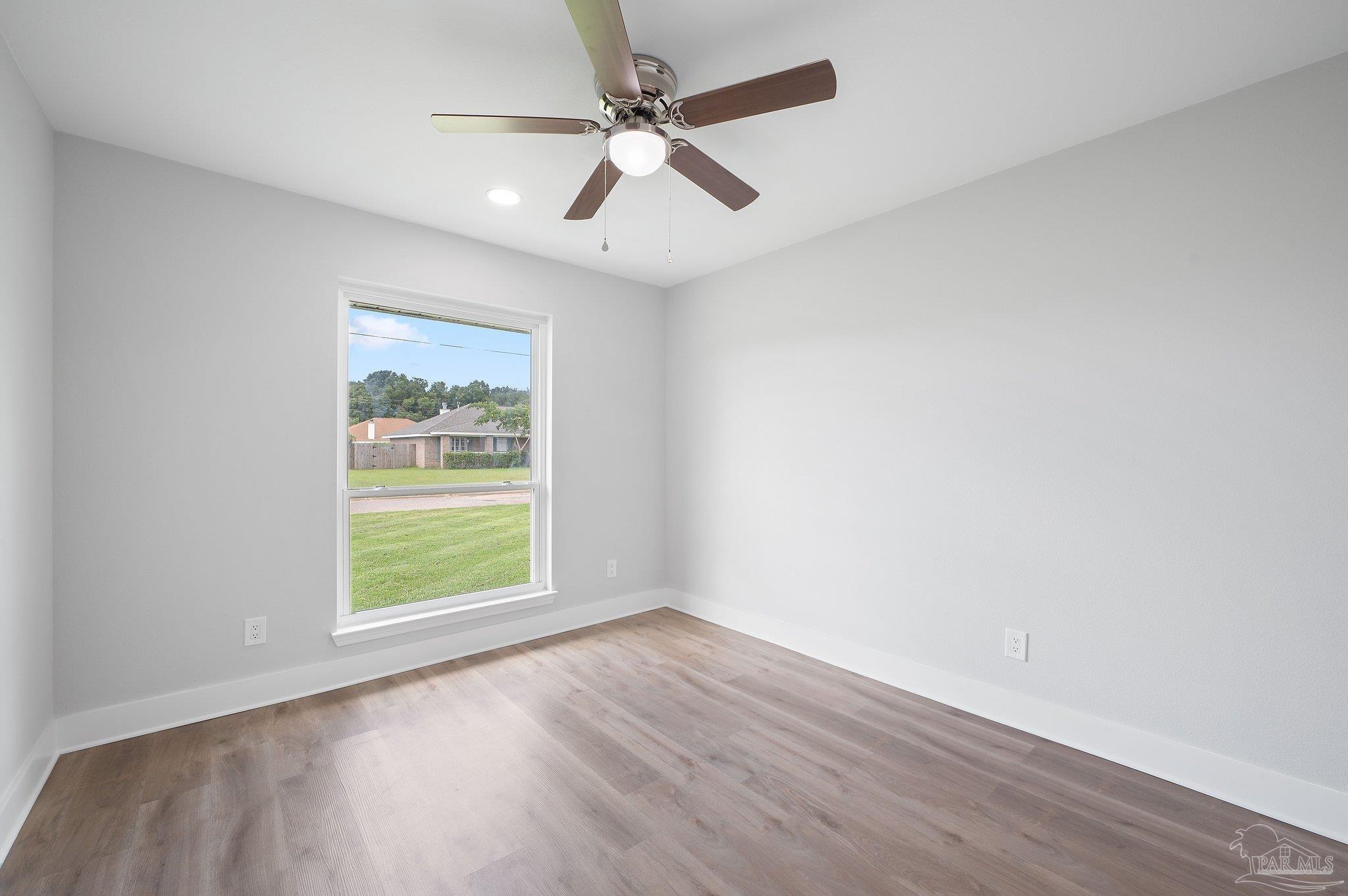 4290 Idell Lane Pace, FL 32571 - Photo 34 of 45 an empty room with wooden floor ceiling fan and windows
