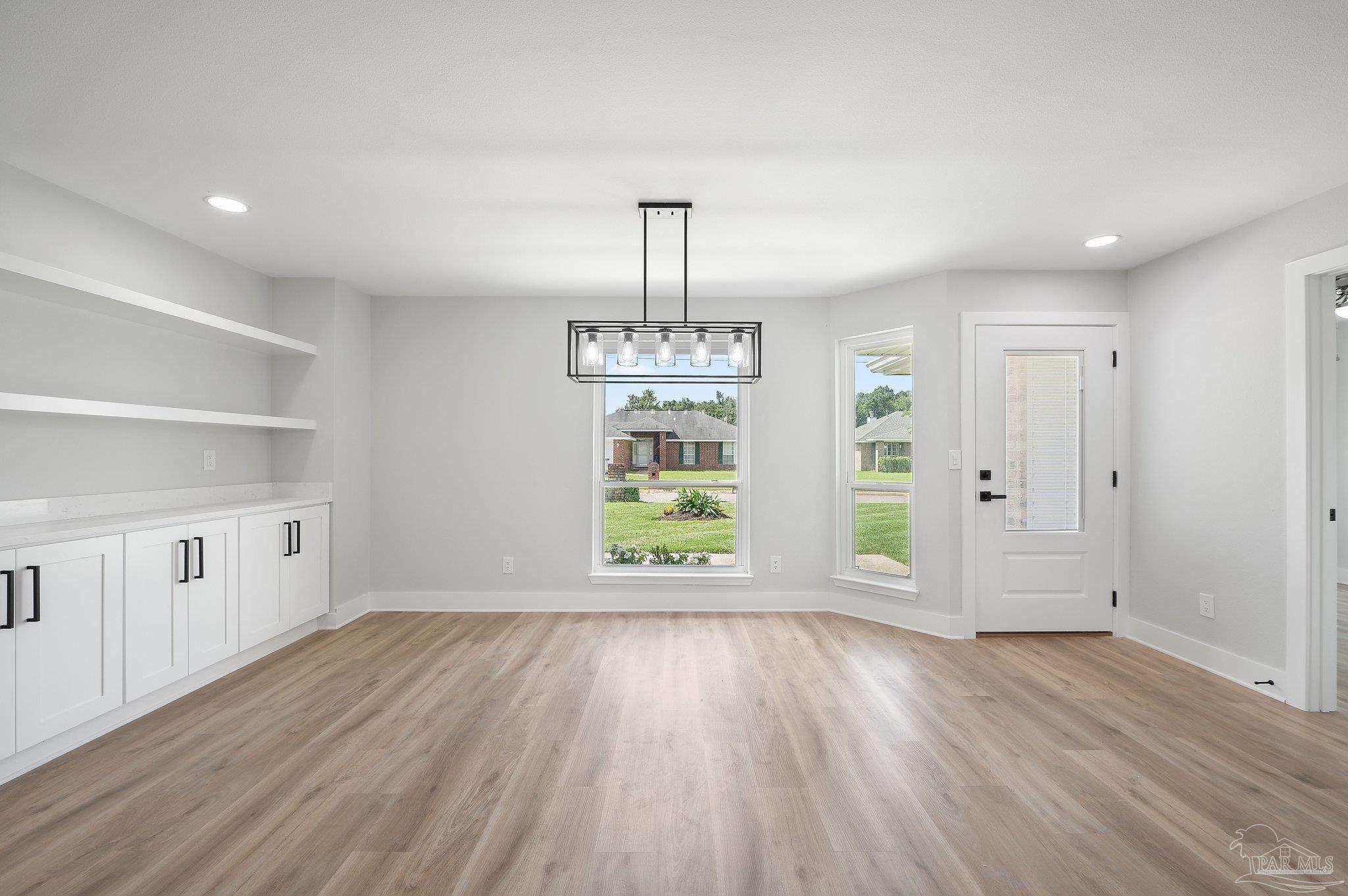 4290 Idell Lane Pace, FL 32571 - Photo 4 of 45 an empty room with wooden floor cabinet and windows