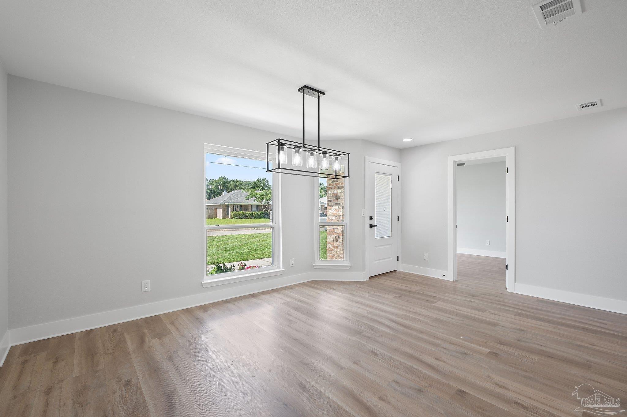 4290 Idell Lane Pace, FL 32571 - Photo 5 of 45 an empty room with wooden floor staircase and windows