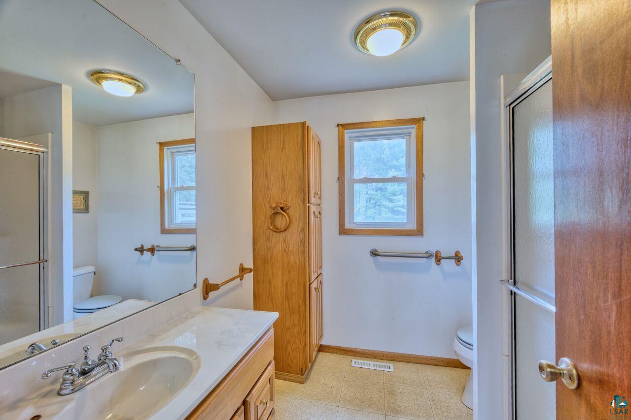 4755 Judd Road Gilbert, MN 55741 - Photo 14 of 50 Bathroom with toilet, baseboards, vanity, and a shower with shower door