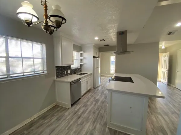 a kitchen with a stove chandelier and wooden floor