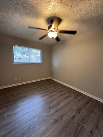 an empty room with wooden floor chandelier fan and windows