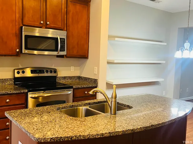 a kitchen with kitchen island granite countertop a sink a stove and a microwave