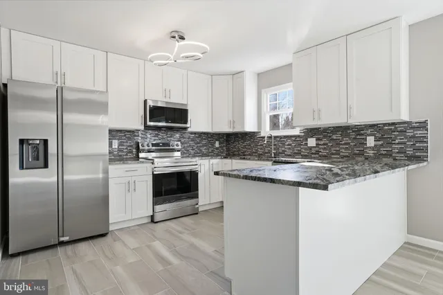 a kitchen with granite countertop a stove sink and refrigerator