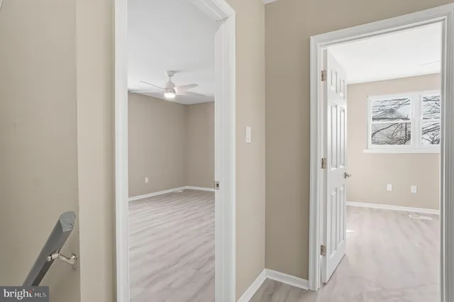 a view of a hallway with wooden floor and a bathroom