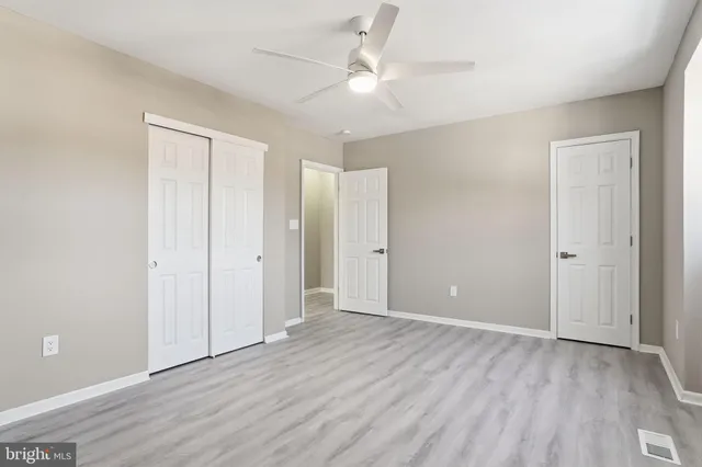 an empty room with wooden floor and ceiling fan