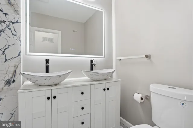 a bathroom with a granite countertop sink and a toilet