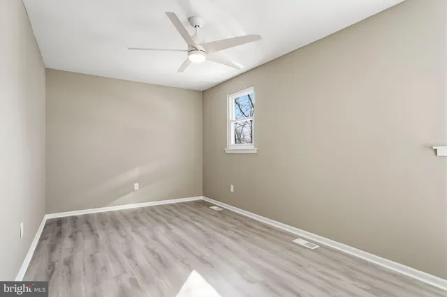 an empty room with a window and ceiling fan