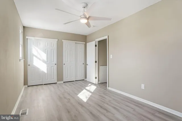 an empty room with wooden floor and a ceiling fan