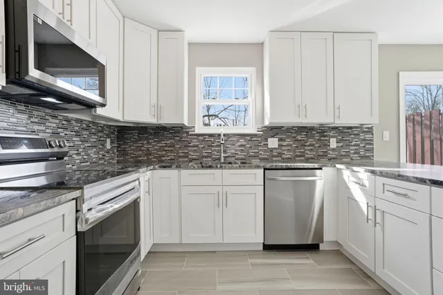 a kitchen with stainless steel appliances granite countertop white cabinets a stove a sink and dishwasher