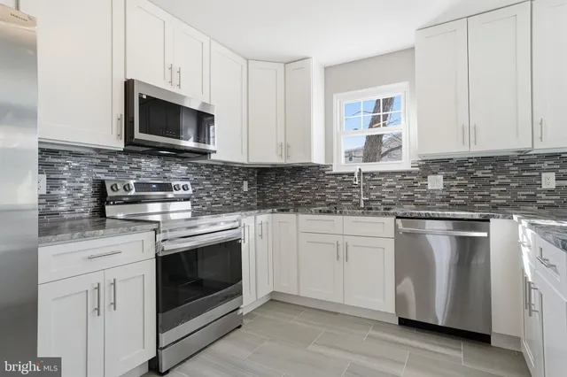 a kitchen with stainless steel appliances granite countertop white cabinets granite counter tops and a wooden floors