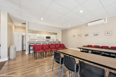 a room with stainless steel appliances kitchen island granite countertop a dining table chairs and a refrigerator