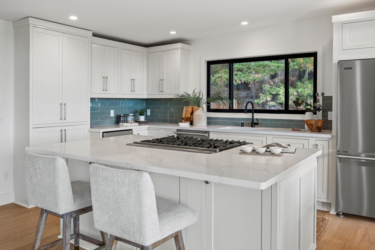 4171 Sunset Lane Pebble Beach, CA 93953 - Photo 14 of 38 a kitchen with kitchen island a stove a refrigerator a sink and white cabinets with wooden floor