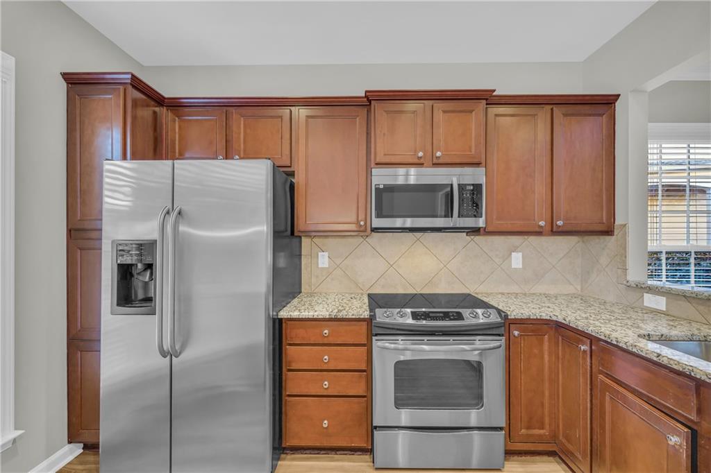 6116 Longleaf Drive Hoschton, GA 30548 - Photo 11 of 46 a kitchen with granite countertop a refrigerator stove and microwave