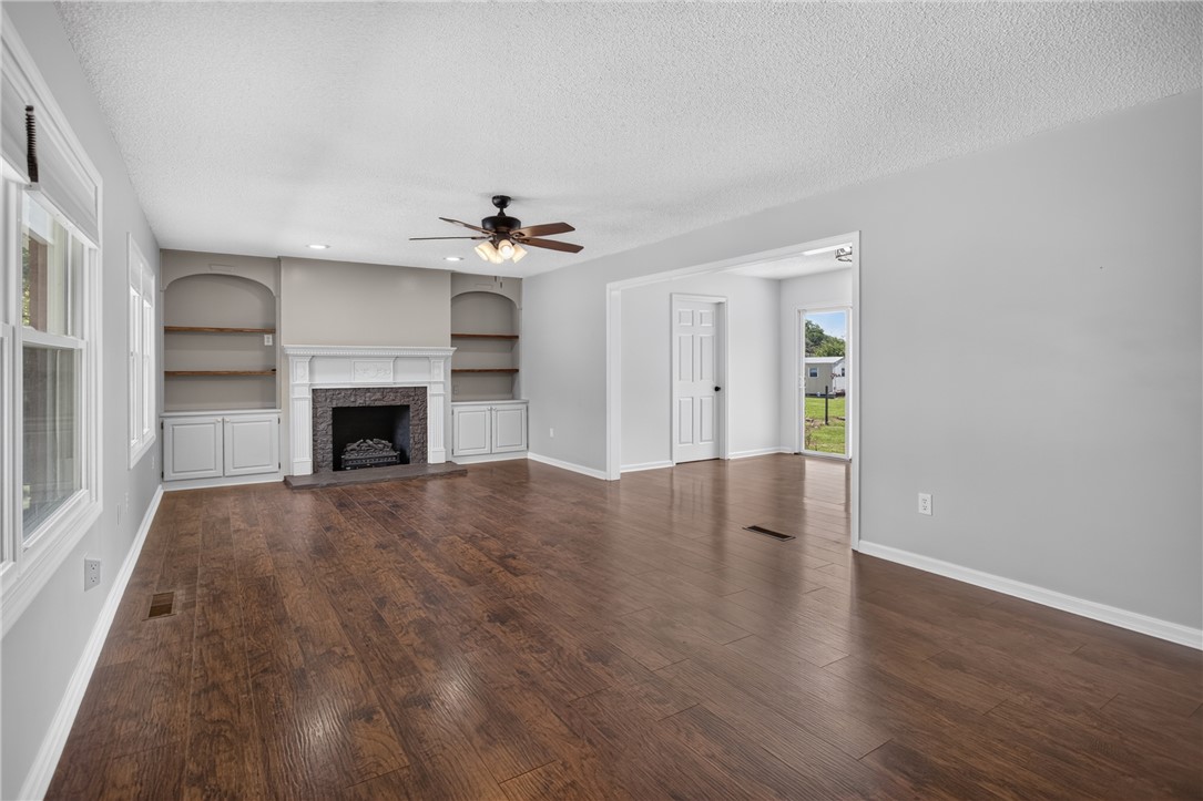 113 Greenfield Avenue Pendleton, SC 29670 - Photo 3 of 40 A generous living room features rich wood flooring, a striking fireplace, and built-in shelving.