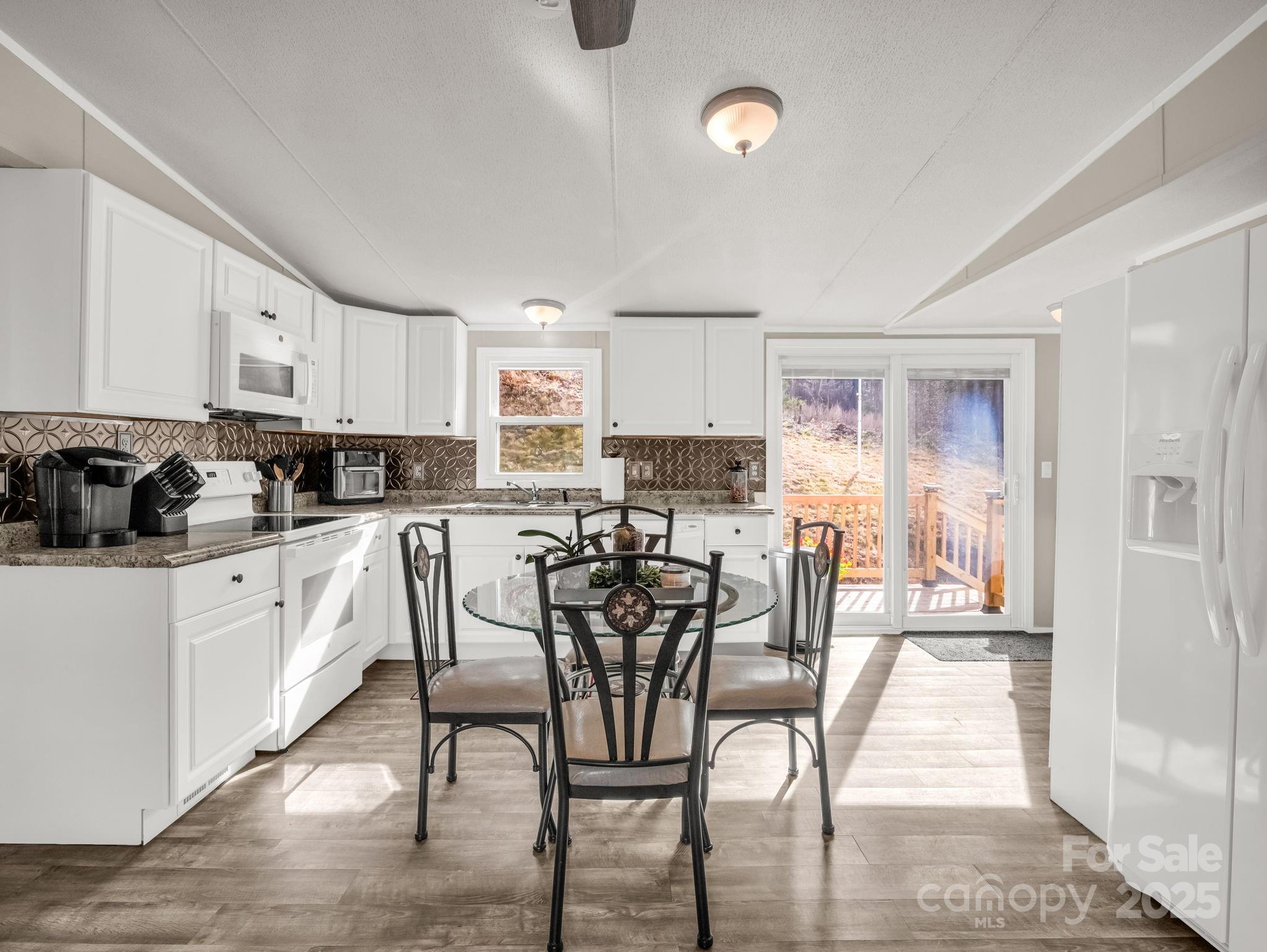 a kitchen with stainless steel appliances granite countertop a stove top oven a sink a refrigerator with white cabinets and wooden floor