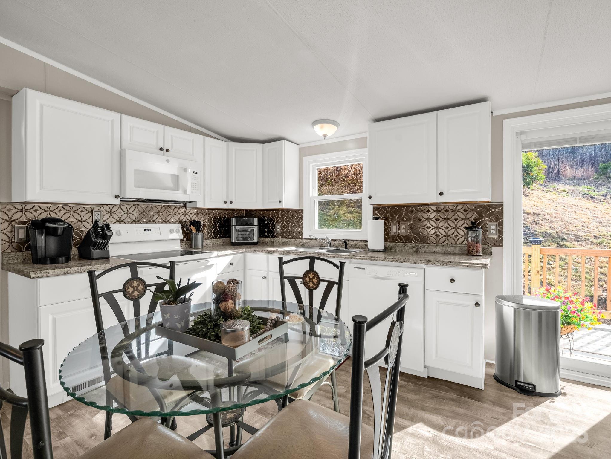 106 Hazy Day Swannanoa, NC 28778 - Photo 6 of 30 a kitchen with stainless steel appliances kitchen island granite countertop a table chairs microwave and sink