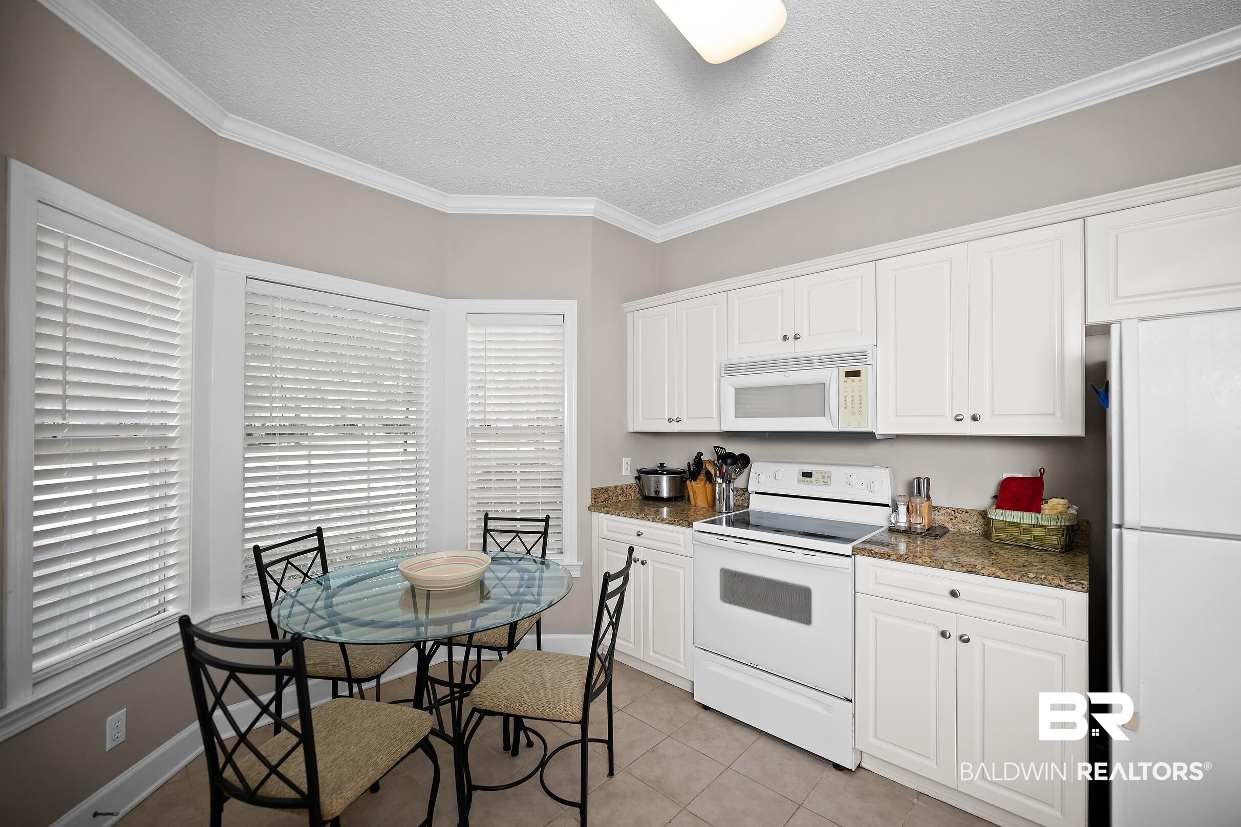 430 West Fort Morgan Road, Unit 704 Gulf Shores, AL 36542 - Photo 9 of 35 Kitchen featuring white cabinetry, a built-in microwave, a range, a refrigerator, and speckled countertops