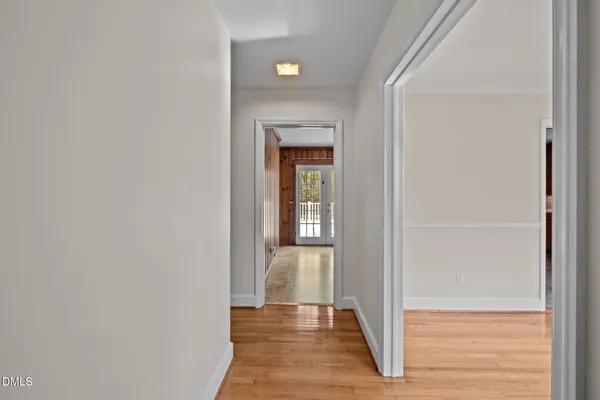a view of an empty room with wooden floor and a ceiling fan
