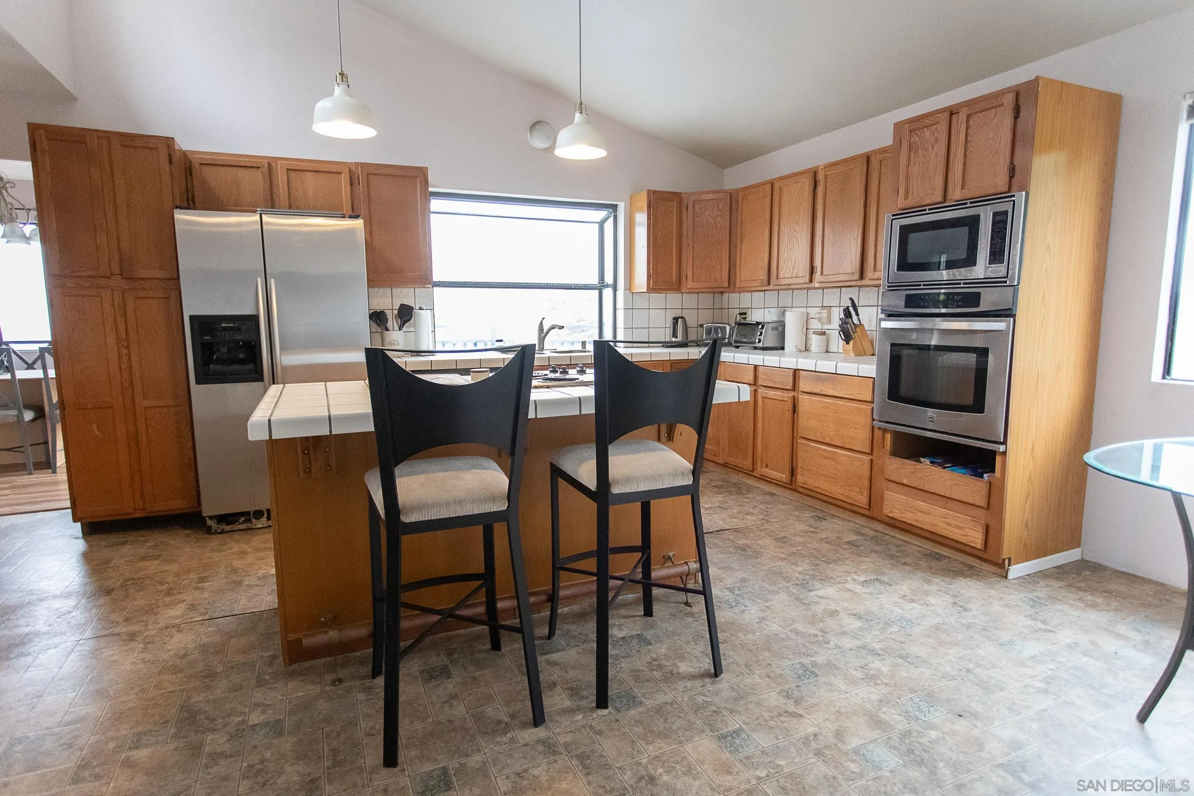 9802 Eucalyptus Street Spring Valley, CA 91977 - Photo 6 of 40 a kitchen with stainless steel appliances a dining table chairs microwave and refrigerator