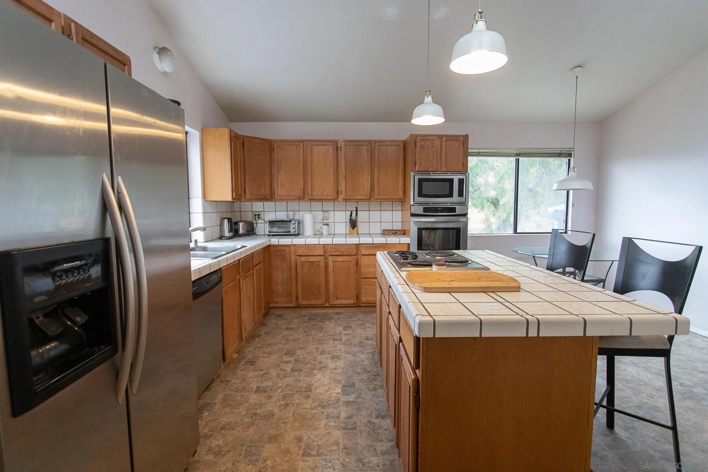 9802 Eucalyptus Street Spring Valley, CA 91977 - Photo 7 of 40 a kitchen with stainless steel appliances granite countertop a refrigerator a sink a stove a microwave and island