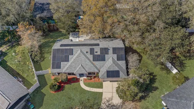 an aerial view of a house with swimming pool and large trees