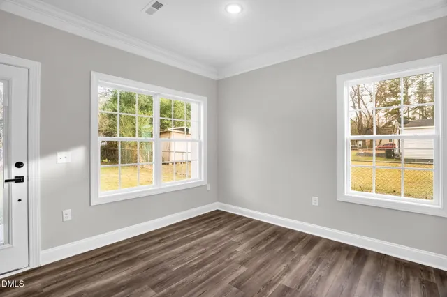 a view of an empty room with wooden floor and a window