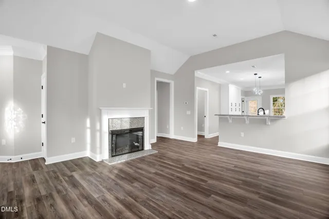 an empty room with wooden floor fireplace and windows