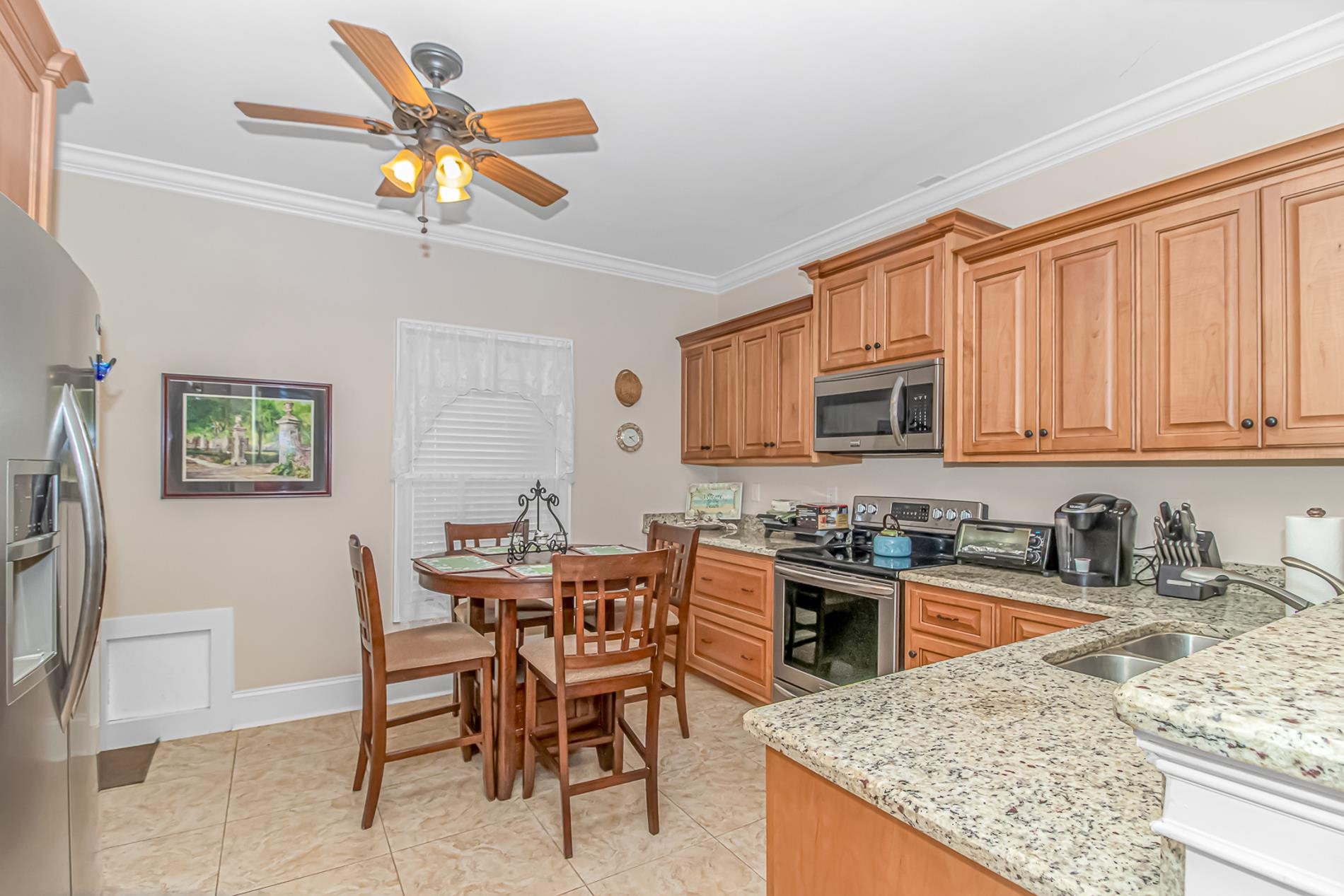 309 North Myrtle Drive Surfside Beach, SC 29575 - Photo 29 of 40 Kitchen with stainless steel appliances, light stone countertops, ceiling fan, ornamental molding, and brown cabinets