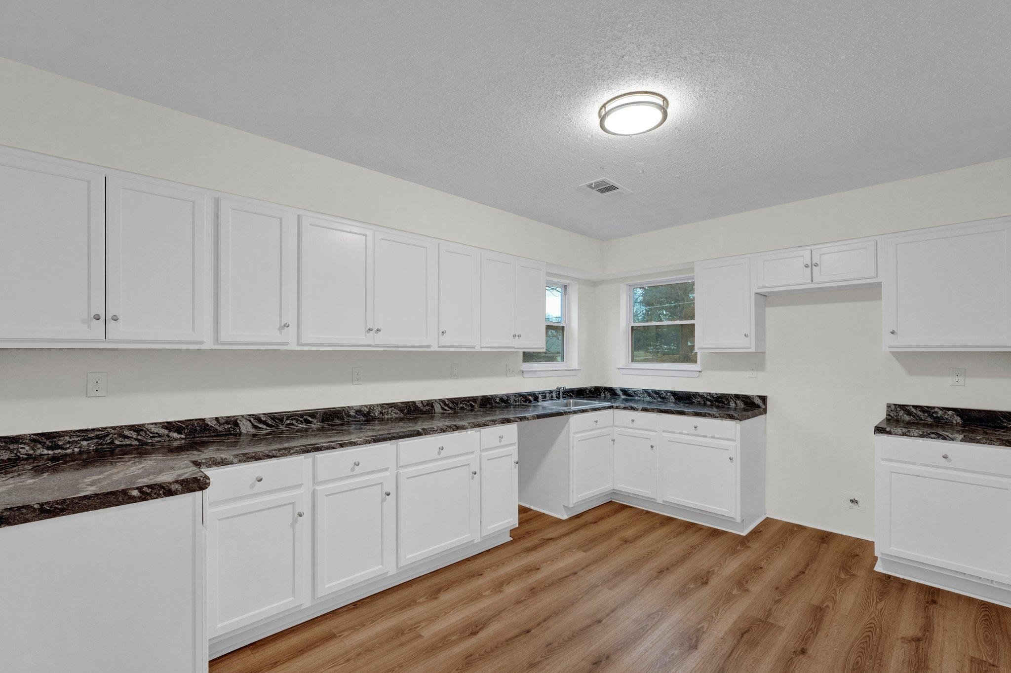 4195 Bishops Bridge Road Memphis, TN 38118 - Photo 8 of 19 a kitchen with granite countertop a stove a sink and white cabinets with wooden floor