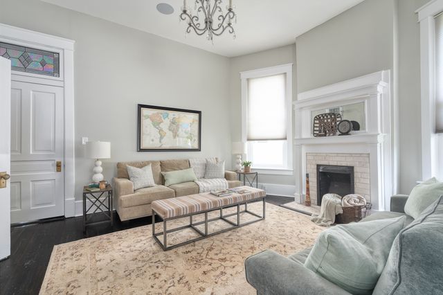 a living room with furniture two windows and a fireplace