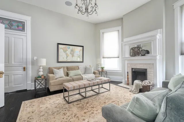 a living room with furniture two windows and a fireplace