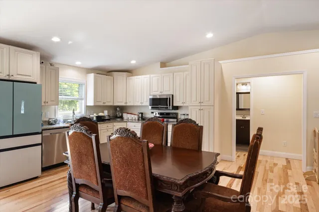 a kitchen with stainless steel appliances granite countertop a refrigerator a stove a sink dishwasher with a dining table and chairs