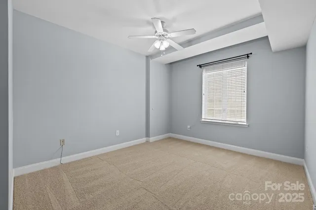 an empty room with chandelier fan and windows