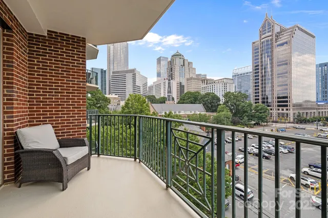 a view of a city from a balcony with wooden chairs