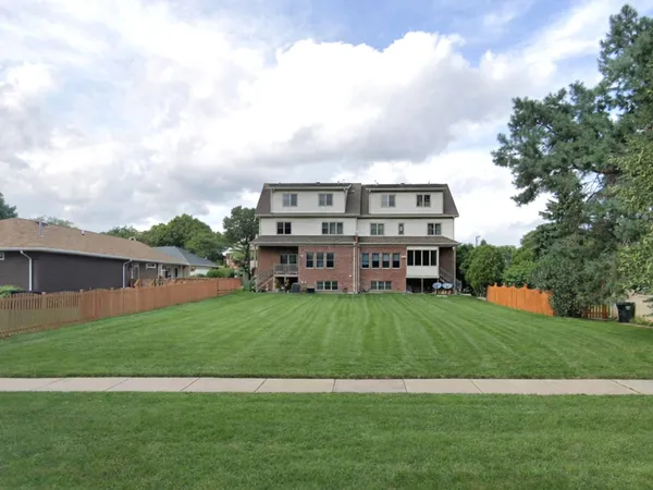 a view of a big house with a big yard and large trees