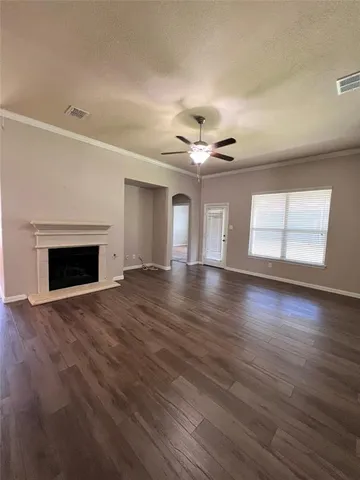 a view of an empty room with wooden floor fireplace and a window