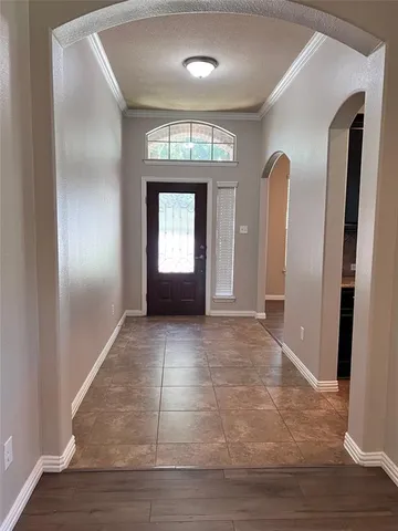 a view of an empty room with wooden floor and a mirror