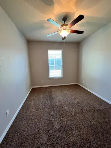 an empty room with a ceiling fan and window
